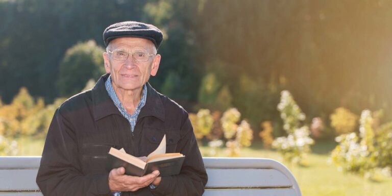 Anziano che legge un libro al parco